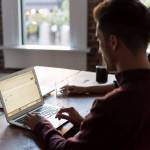 man operating laptop on top of table